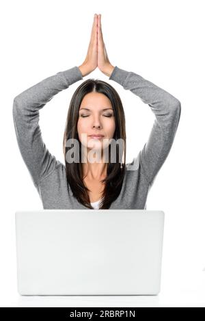 Jolie Jeune femme Cheveux Longs méditant avec les mains sur la tête et ferma les yeux en face d'un ordinateur portable, isolé sur fond blanc Banque D'Images