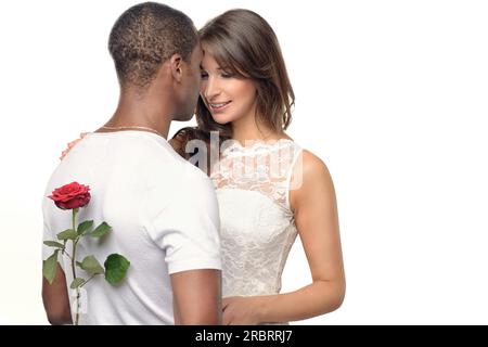 Jeune homme romantique avec une jolie femme cachant une rose rouge derrière son dos alors qu'il se prépare à la surprendre le jour de la Saint Valentin ou avec une proposition de mariage Banque D'Images