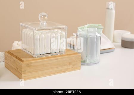 De nombreux tampons différents et produits de soins personnels sur la table blanche près du mur beige Banque D'Images