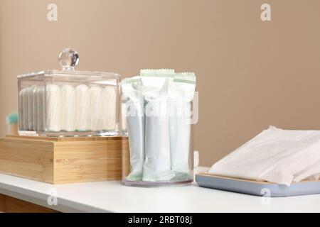 Beaucoup de tampons différents sur la table blanche près du mur beige. Produit hygiénique menstruel Banque D'Images