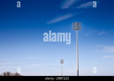 Image des projecteurs de stade dans l'après-midi, avec un ciel bleu, utilisé pour fournir de la lumière aux événements sportifs dans un stade. Banque D'Images