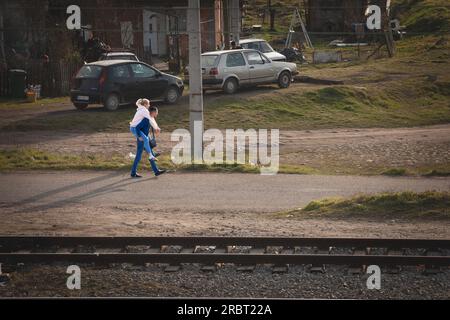 Photo d'un couple, homme et femme, jeunes, serbes, marchant dans les rues de Mladenovac, Serbie, la fille étant soulevée sur le dos de l'homme. Banque D'Images