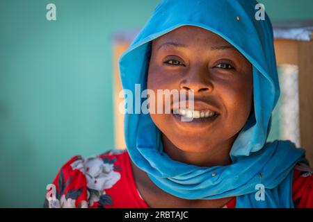 Radieuse dame tchadienne dans le hijab bleu vibrant confère un sourire captivant Banque D'Images