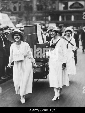 New York, New York : vers 1917 trois femmes sur la Cinquième Avenue tirant un orgue et vendant des chansons pour recueillir des fonds pour l'effort de guerre. Banque D'Images