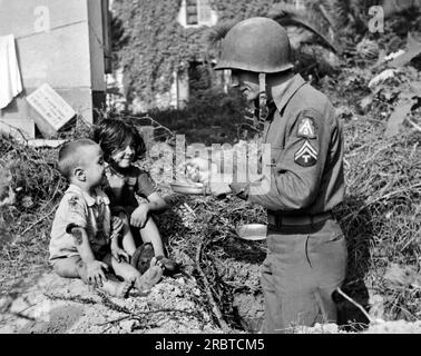 Italie : le 6 octobre 1943 un soldat américain partage ses rations avec deux ventouses italiennes affamées. Banque D'Images