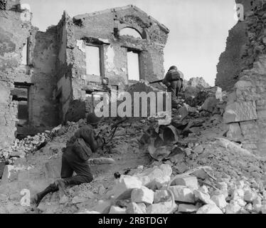 Bretagne, France 17 juin 1944 membres d'une unité d'ingénieurs se déplaçant à travers les ruines de bâtiments bombardés en Bretagne, France Banque D'Images