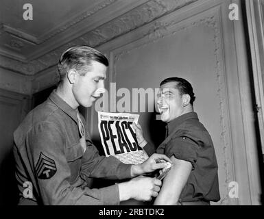 Paris, France : 14 août 1945 A États-Unis Soldat de l'armée à Paris détient le dernier exemplaire de The Stars and Stripes annonçant la reddition du Japon avec le titre de «PAIX». Banque D'Images