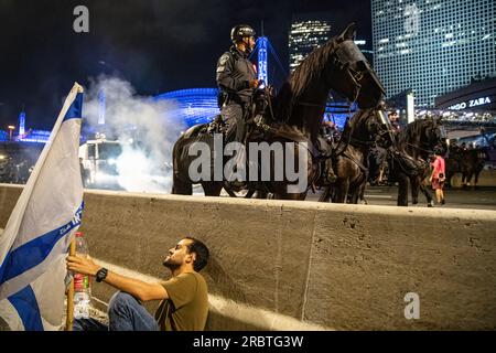 Les manifestants anti-réforme se cachent des policiers à cheval et des canons à eau pendant la manifestation. Des milliers d'Israéliens sont descendus dans les rues et ont bloqué l'autoroute Ayalon à tel Aviv, affrontant la police qui a utilisé des canons à eau et des policiers à cheval et arrêté pour disperser les manifestants après que le chef de la police de tel Aviv Amichai Eshed ait annoncé sa démission de la force. Banque D'Images