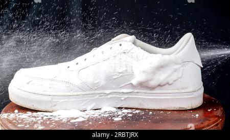 Chaussures en cuir blanc vaporisées de mousse nettoyante. Entretien des chaussures en cuir. Banque D'Images