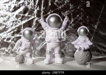 Trois jouets en plastique figurine astronaute sur fond argent espace de copie. Concept de voyage hors terre, vols commerciaux privés de spaceman. Missions spatiales et durabilité Banque D'Images