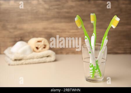 Brosses à dents en verre sur table beige. Espace pour le texte Banque D'Images