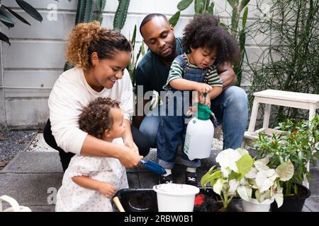 Famille afro-américaine avec deux enfants se lier dans le jardin et planter et grandir ensemble Banque D'Images