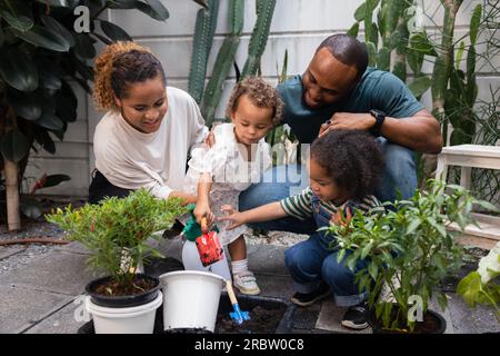 Famille afro-américaine avec deux enfants se lier dans le jardin et planter et grandir ensemble Banque D'Images
