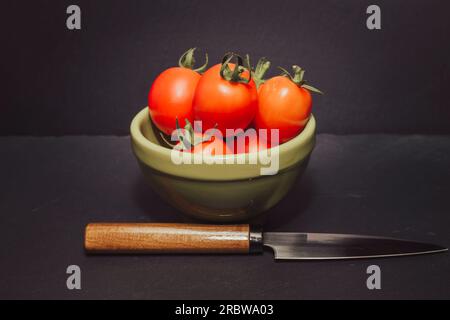 Tomates Piccadilly sur un bol vert. Fruit de taille moyenne, de forme ovale avec une saveur intensément sucrée. Tomates utilisées en cuisine et excellente mangée crue. Banque D'Images