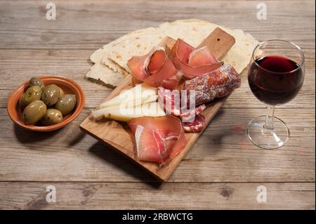 Jambon cru sarde, saucisse de porc crue sarde, assiette de fromage pecorino sarde, olives, pain Carasau, vin rouge, Sardaigne, Italie, Europe Banque D'Images