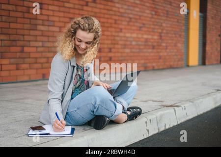 Jeune femme écrivant dans le bloc-notes sur la rue Banque D'Images