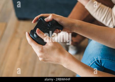 Crop gamer avec manette de jeu jouant au jeu vidéo Banque D'Images