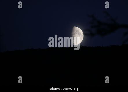 Lune partielle sur bleu foncé avec horizon légèrement visible. Banque D'Images