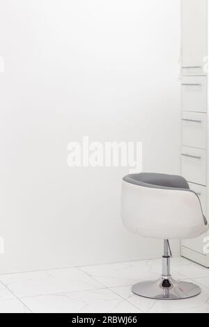Chaise en plastique blanc moderne dans le plancher en céramique intérieur de salle blanche. Espace de copie. Banque D'Images