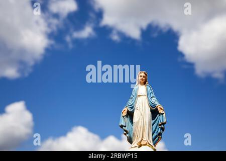 Assomptio de Marie. Statue de la Vierge Marie avec le ciel bleu avec des nuages blancs. Banque D'Images