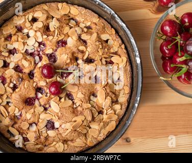Tarte aux cerises maison avec des amandes dans une poêle ronde sur une table en bois Banque D'Images