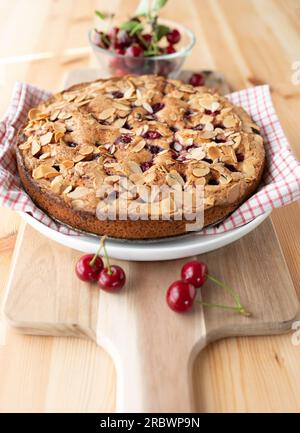 Gâteau aux cerises ou tarte aux cerises avec des amandes et des cerises acides sur une table en bois clair Banque D'Images