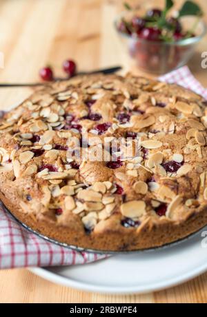 Gâteau aux cerises ou tarte aux cerises avec des amandes et des cerises acides sur une table en bois clair Banque D'Images