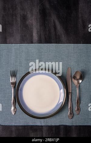 Toile de table bleue avec une plaque sur fond noir de tableau noir. Pose à plat. Vue de dessus. Banque D'Images