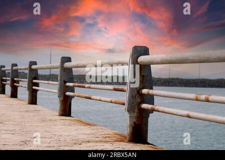 Une clôture rouillée avec une mer bleue dans l'arrière-plan.Rusty main de fer, belle mer et ciel paysage vue entre la rampe rouillée. Banque D'Images