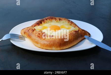 Assiette d'Adjaruli Khachapuri, un délicieux pain géorgien traditionnel garni de fromage et d'œuf Banque D'Images