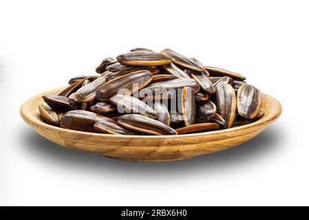 Vue latérale pile de graines de tournesols salées dans une plaque de bois isolée sur fond blanc avec chemin de découpage. Banque D'Images