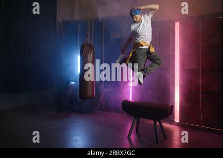 Jeune adulte b-boy breakdancer sautant sur l'air au-dessus du fond de la salle de gym loft Banque D'Images