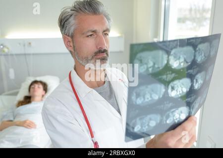 médecin étudiant les résultats de scan patient dans le lit d'hôpital en arrière-plan Banque D'Images