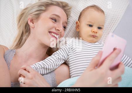 femme avec un bébé faisant un selfie couché Banque D'Images