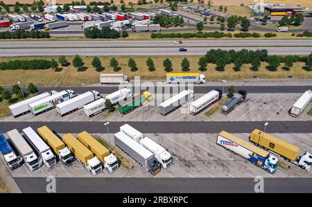 Grimma, Allemagne. 11 juillet 2023. De nombreux camions stationnent dans la zone de service Muldental Süd sur l’autoroute 14. Lors de son test des zones de service, le Club automobile allemand (ADAC) a examiné 40 installations en termes d’installations extérieures/accès, d’offres gastronomiques, d’installations sanitaires, de prix et de services. L'établissement près de Grimma a été classé «bon». Dans l'ensemble, l'ADAC a trouvé que la plupart des installations étaient en très bon état et visuellement très propres. L'ADAC décrit les prix élevés comme la plus grande gêne lors de la visite d'une aire de repos. (Photo aérienne avec drone) crédit : Jan Woitas/dpa/Alamy Live News Banque D'Images