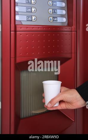 Femme prenant la tasse de boisson du distributeur automatique de café, closeup Banque D'Images