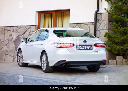 MURZASICHLE, POLOGNE - 28 AVRIL 2023 : berline blanche hybride Toyota Camry garée en face de l'hôtel à High Tatras en Pologne Banque D'Images