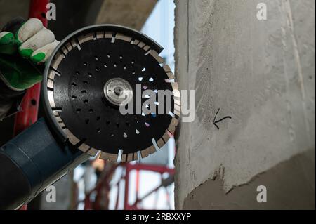 Master coupe un mur en béton avec une scie circulaire diamantée. Banque D'Images