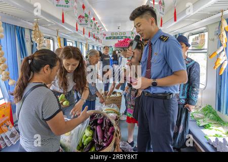 (230711) -- CHONGQING, 11 juillet 2023 (Xinhua) -- des passagers achètent des spécialités locales à bord du train n° 5630 de Zunyi, dans la province du Guizhou, dans le sud-ouest de la Chine, à la municipalité de Chongqing, dans le sud-ouest de la Chine, le 11 juillet 2023. Les trains n ° 5630 et 5629 sont des «trains lents» circulant entre Zunyi de la province de Guizhou et la municipalité de Chongqing dans le sud-ouest de la Chine. Les autorités ferroviaires locales ont organisé des marchés et des spectacles à bord, qui permettent aux villageois vivant le long de l'itinéraire des trains de vendre des marchandises aux passagers et, parallèlement, d'offrir aux passagers une expérience de voyage spéciale. (Xinhua/Huang Wei) Banque D'Images