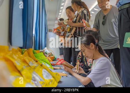 (230711) -- CHONGQING, 11 juillet 2023 (Xinhua) -- des passagers achètent des spécialités locales à bord du train n° 5630 de Zunyi, dans la province du Guizhou, dans le sud-ouest de la Chine, à la municipalité de Chongqing, dans le sud-ouest de la Chine, le 11 juillet 2023. Les trains n ° 5630 et 5629 sont des «trains lents» circulant entre Zunyi de la province de Guizhou et la municipalité de Chongqing dans le sud-ouest de la Chine. Les autorités ferroviaires locales ont organisé des marchés et des spectacles à bord, qui permettent aux villageois vivant le long de l'itinéraire des trains de vendre des marchandises aux passagers et, parallèlement, d'offrir aux passagers une expérience de voyage spéciale. (Xinhua/Huang Wei) Banque D'Images