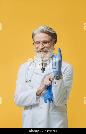 Portrait d'un médecin senior souriant portant des gants en caoutchouc Banque D'Images