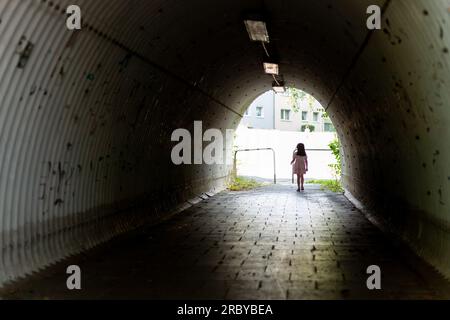 Femme marchant au milieu d'un tunnel dans un jour sombre. Banque D'Images