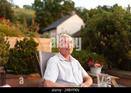 Portrait d'un homme âgé assis dans le jardin par une journée ensoleillée Banque D'Images