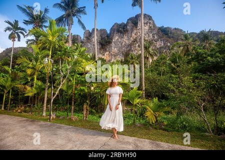 Jeune femme dans le chapeau de paille aime se promener tranquillement parmi le vert luxuriant Banque D'Images