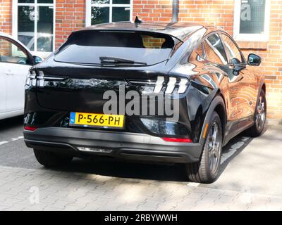 Uelsen, Allemagne - juin 27 2023 Une Ford Mustang Mach-E noire stationnée devant un mur de briques. Le mur se reflète dans la voiture. Cette Mustang est tout elec Banque D'Images