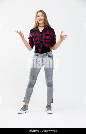 Une jeune personne portant une chemise à carreaux pose sur un fond blanc en position debout. Banque D'Images