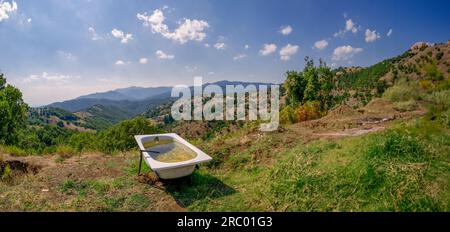 Paysage panoramique dans le nord de la Grèce où au premier plan, vous pouvez voir une baignoire utilisée comme un bassin d'arrosage pour les animaux et au loin un mountai Banque D'Images