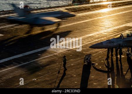 Mer Adriatique, eaux internationales. 08 juillet 2023. Mer Adriatique, eaux internationales. 08 juillet 2023. Un marin américain observe un avion de chasse Super Hornet de la Navy F/A-18E, attaché au Tomcatters of Strike Fighter Squadron 31, atterrit au coucher du soleil depuis le poste d'envol à bord du porte-avions de classe Nimitz USS Gerald R. Ford opérant sur la mer Adriatique, le 8 juillet 2023 au large des côtes albanaises. Crédit : MC2 Nolan Pennington/États-Unis Navy photo/Alamy Live News Banque D'Images