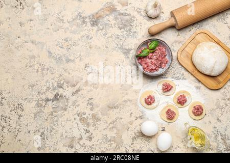 Pâte crue avec viande hachée et ingrédients pour préparer des boulettes sur fond beige Banque D'Images