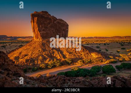 Lever de soleil à couper le souffle projetant des teintes dorées sur la butte stoïque, capturée depuis le point de vue de l'arche de Djoula, Ennedi, Tchad Banque D'Images
